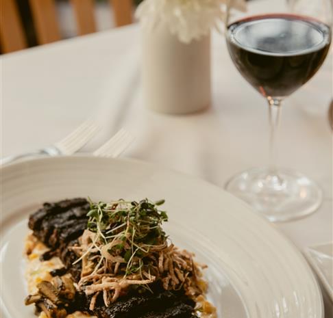 a meat dish with a glass of wine