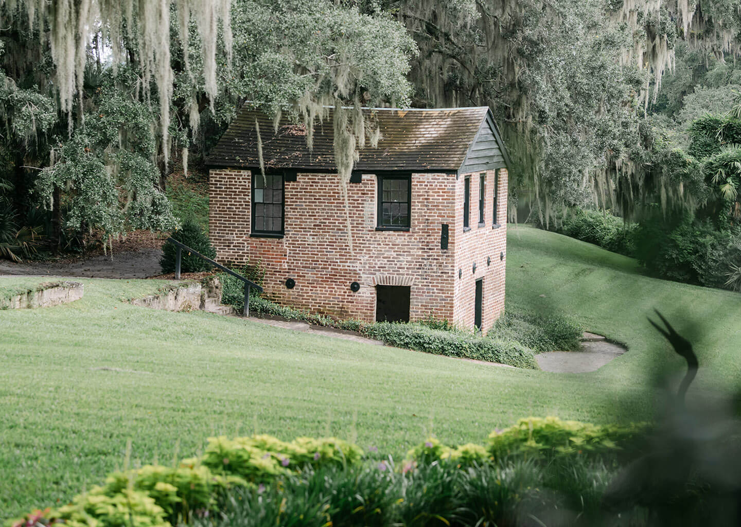 A brick building in the woods surrounded by wispy trees